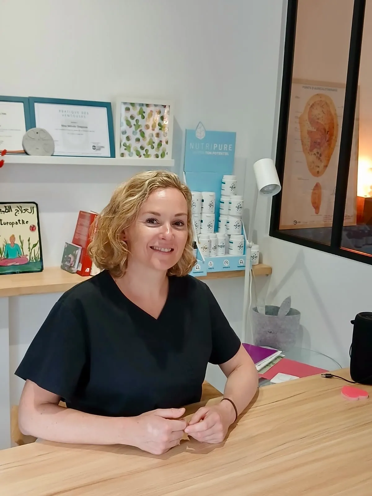 Mélodie Despoisse souriante, assise à son bureau dans son cabinet de consultation