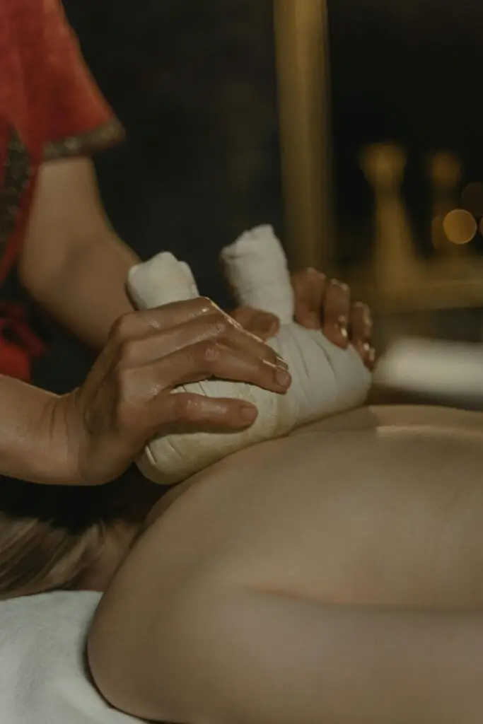 Massage du dos réalisé avec des pochons chauds enveloppés de tissu