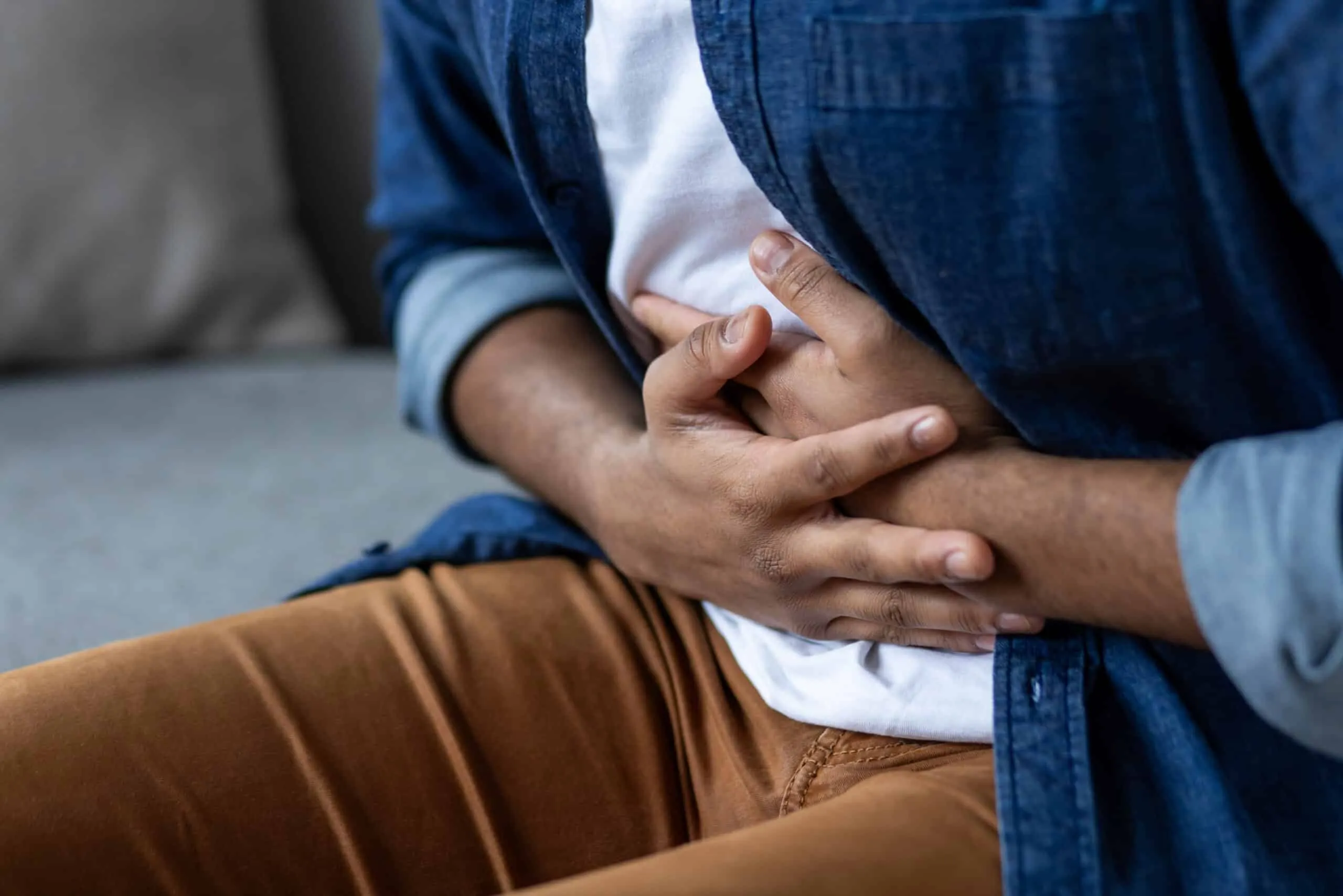 Homme se tenant le ventre des deux mains en raison d’un inconfort digestif